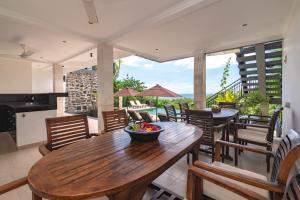 Pabean BulelengにあるVilla Jempiring - Splendid 180° Ocean View Villaの木製のテーブルと椅子のあるキッチンとダイニングルーム