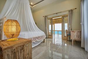 a bedroom with a bed and a table with a lamp at Arungan Villas in Amed