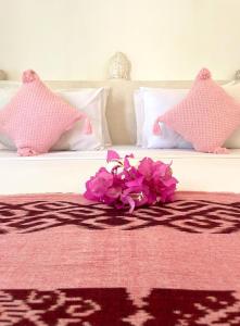 un bouquet de fleurs roses sur un lit dans l'établissement The Barefoot Blondie Village, à Gili Air