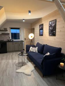 a living room with a blue couch and a kitchen at Anielski Apartament in Szaflary