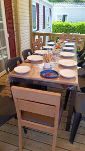 a large wooden table with chairs and plates on it at Mobil home 3 ch domaine de kerlann pont aven wifi inclu in Pont-Aven
