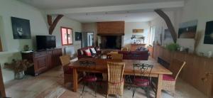 a dining room and living room with a table and chairs at Le lit de la Saâne in Auzouville-sur-Saâne