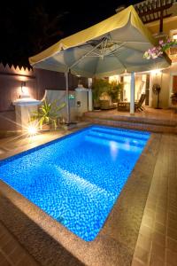 einen Swimmingpool in der Nacht mit Sonnenschirm in der Unterkunft Dar 66 Plunge Pool Resort Townhouses in Ras al Khaimah