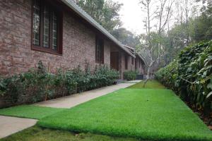 a brick building with a yard of green grass at The Pear Tree in Yercaud