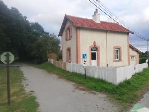 uma pequena casa com uma cerca branca ao lado de uma estrada em Gîte garde-barrière 2 chambres em Saint-Guen