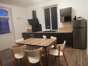 een keuken met een houten tafel en witte stoelen bij Gîte garde-barrière 2 chambres in Saint-Guen