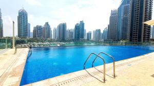 a large swimming pool with a city skyline in the background at LUX The Cayan Superior Suite in The Dubai Marina in Dubai