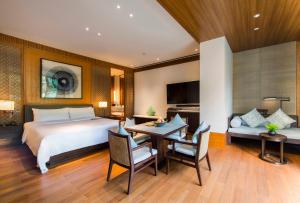 Le Méridien Shimei Bay Beach Resort & Spa في اننينغ: غرفة نوم بسرير وطاولة وكراسي