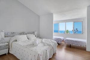 ein weißes Schlafzimmer mit zwei Betten und einem großen Fenster in der Unterkunft Adosada con jardín y piscina con acceso al mar - DOÑA LOLA in Sitio de Calahonda + 24 Fotos