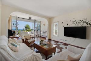 ein Wohnzimmer mit Couch und Flachbildfernseher in der Unterkunft Adosada con jardín y piscina con acceso al mar - DOÑA LOLA in Sitio de Calahonda