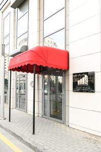 einem roten Regenschirm auf einem Bürgersteig vor einem Gebäude in der Unterkunft Sport Plaza Hotel & Apartments in Baku