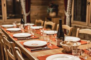 una mesa larga con platos y copas y una botella de vino en La Ferme du Var, en La Clusaz