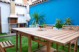 una mesa de madera y sillas en un patio con una pared azul en El Merendero, en Ateca