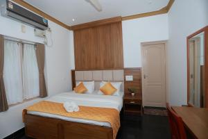 Schlafzimmer mit einem Bett mit orangefarbenen und weißen Kissen in der Unterkunft Ideal Ayurvedic Resort Kovalam in Kovalam