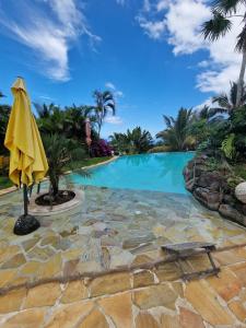 una piscina con sombrilla amarilla y un patio de piedra en Maryse’ House, en Les Avirons