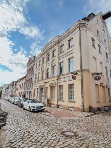 un gran edificio con coches estacionados frente a él en Altstadtbude 27 - modernes Apartment in historischer Altstadt en Rostock