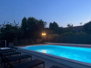 a large swimming pool with two chairs and a street light at Logis La Thomasse in Aurillac