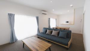 un soggiorno con divano blu e tavolo di BiBi Hotel 宮古空港前 SouthTower a Miyakojima