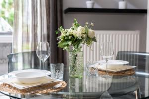 uma mesa de vidro com um vaso com flores em Cozy Apartment Karpia 17 with Terrace & PARKING in Poznań by Renters em Poznań