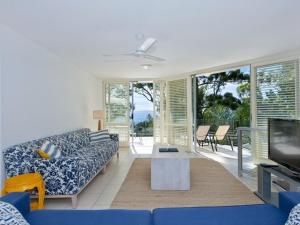 een woonkamer met een blauwe bank en een tv bij Kareka Apartment 2, Little Cove in Noosa Heads