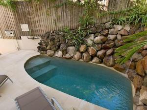 een zwembad met stoelen en een rotswand bij Kareka Apartment 2, Little Cove in Noosa Heads