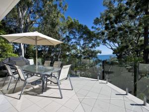 een tafel en stoelen met een parasol op een patio bij Kareka Apartment 2, Little Cove in Noosa Heads