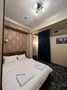 een slaapkamer met een groot bed en 2 handdoeken bij Almaz Hotel Uzbekistan in Tasjkent