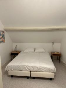 - un lit blanc dans une chambre avec deux tables dans l'établissement Sesimbra Domburg, à Domburg
