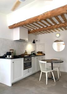 cocina con armarios blancos, mesa y sillas en La terrasse du pont jullian charme et calme dans le cœur historique, en LʼIsle-sur-la-Sorgue