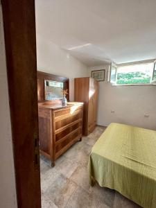 ein Schlafzimmer mit einem Bett, einer Kommode und einem Fenster in der Unterkunft Tentadore in La Caletta