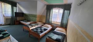 a room with two beds and a tv and windows at Dziubasowka in Poronin