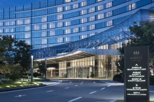 a large glass building with a road in front of it at Grand Barony Qingdao Airport Hotel in Qingdao