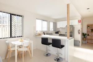 a white kitchen with a white table and chairs at 2 Bedroom! Great Location & Walk to Train in Brisbane