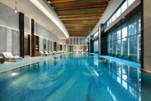 a large swimming pool in a building with windows at Grand Barony Qingdao Airport Hotel in Qingdao