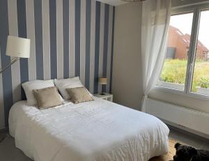 um quarto com uma cama branca e uma janela em La clef des champs em Gruson