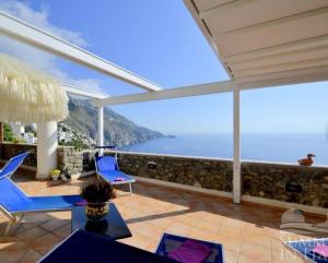 un patio con sillas azules y vistas al océano en Villino Blu en Praiano