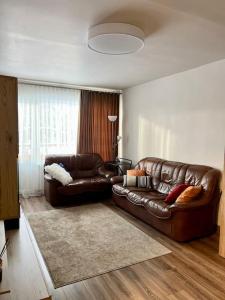 a living room with a leather couch and a window at Refurnished Apartment in Rucava in Rucava