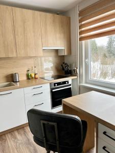 a kitchen with white cabinets and a black chair at Refurnished Apartment in Rucava in Rucava