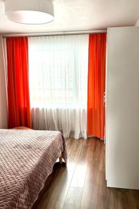 a bedroom with red curtains and a bed and a window at Refurnished Apartment in Rucava in Rucava