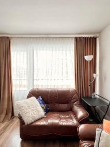 a brown leather couch in a living room with a window at Refurnished Apartment in Rucava in Rucava