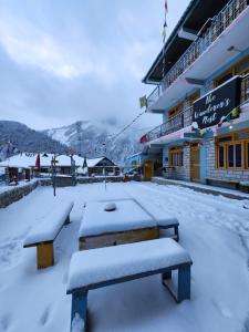 two benches covered in snow in front of a building at LAP Stays - Wanderer's Nest in Chitkal