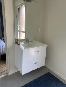 ein weißes Badezimmer mit einem Waschbecken und einem Spiegel in der Unterkunft La clef des champs in Gruson