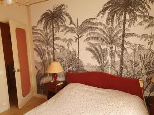 um quarto com uma cama com papel de parede de palmeira em Maison dans le bourg em Les Pieux