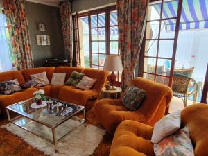 a living room with orange couches and a table at Maison dans le bourg in Les Pieux