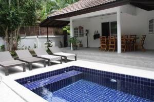 a swimming pool with chairs and a table and a house at Orchid Villa in Ko Tao