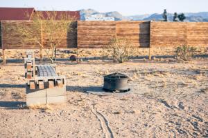un banco y un cubo de basura en un campo de tierra en Casa Del Desierto - Panoramic Views - Pet Friendly - Fire Pit, en Joshua Tree