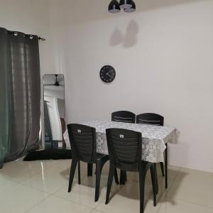 a dining room table with four black chairs and a white table at Ummik Homestay in Tawau