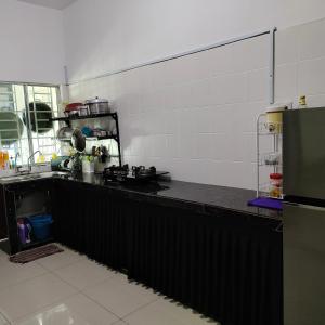a kitchen with a black counter top and a refrigerator at Ummik Homestay in Tawau