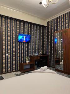 een slaapkamer met een tv aan de muur bij Almaz Hotel Uzbekistan in Tasjkent