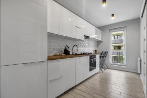 a kitchen with white cabinets and a wooden floor at Warsaw Apartments - Parking, Quiet Neighbourhood - by Rentujemy in Warsaw